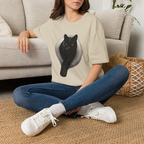 Black unisex T-shirt featuring a realistic black cat graphic with golden eyes and a soft circular glow design.