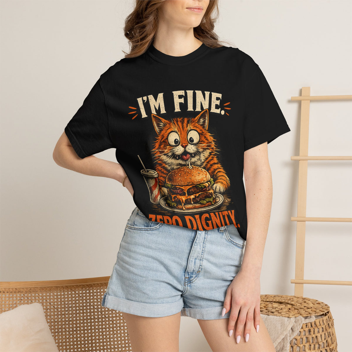 Woman wearing funny orange cat graphic t-shirt with "I'm Fine Zero Dignity Food Always Wins" text and cartoon cat eating a burger, vintage print on black premium cotton unisex tee
